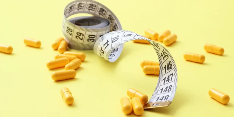 Yellow capsules and a measuring tape on a yellow background, symbolizing Vitamin D and Weight Management.