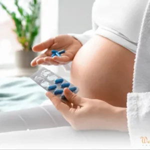 Pregnant woman holding blue cold medicine pills and a blister pack.