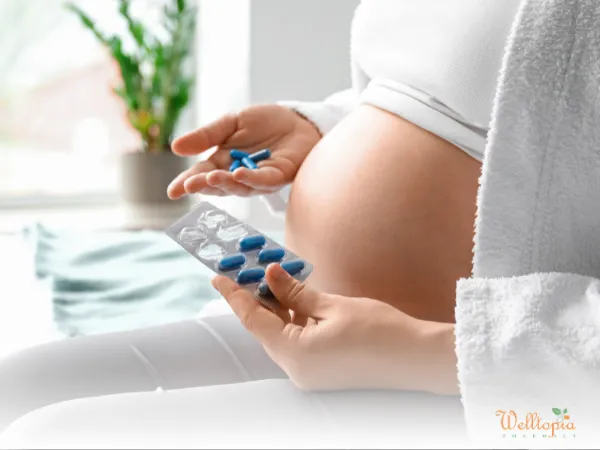 Pregnant woman holding blue cold medicine pills and a blister pack.